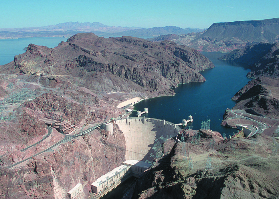 "This is a picture of the Hoover Dam. The picture has the dam in the background and flowing water in the foreground below the dam.">